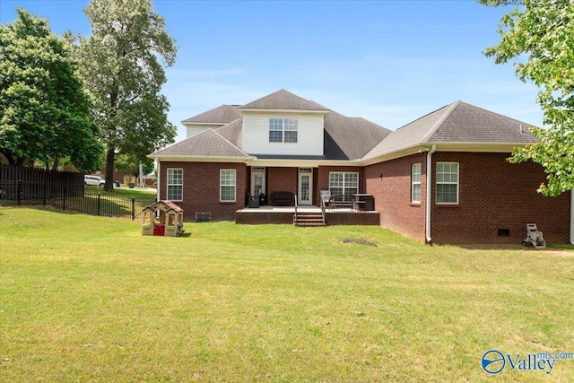 rear view of house featuring brick siding, fence, and a yard