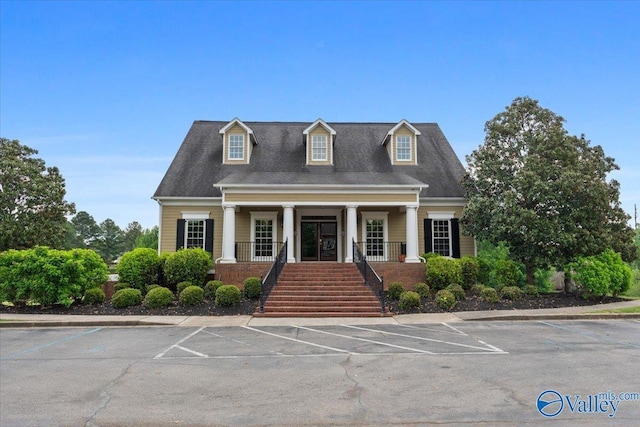 view of front of house featuring a porch, uncovered parking, and stairway