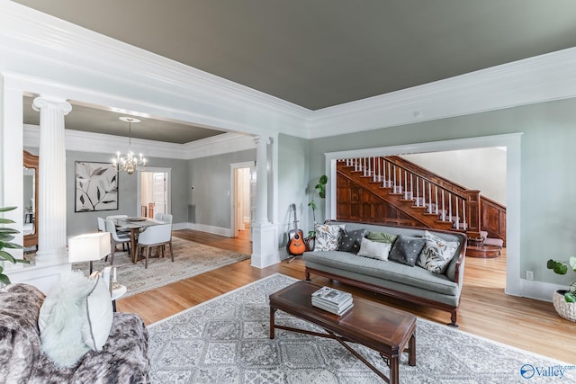 living room with a notable chandelier, decorative columns, light hardwood / wood-style flooring, and ornamental molding