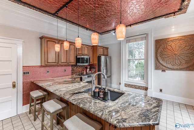 kitchen featuring stainless steel appliances, dark stone countertops, ornamental molding, pendant lighting, and light tile patterned floors