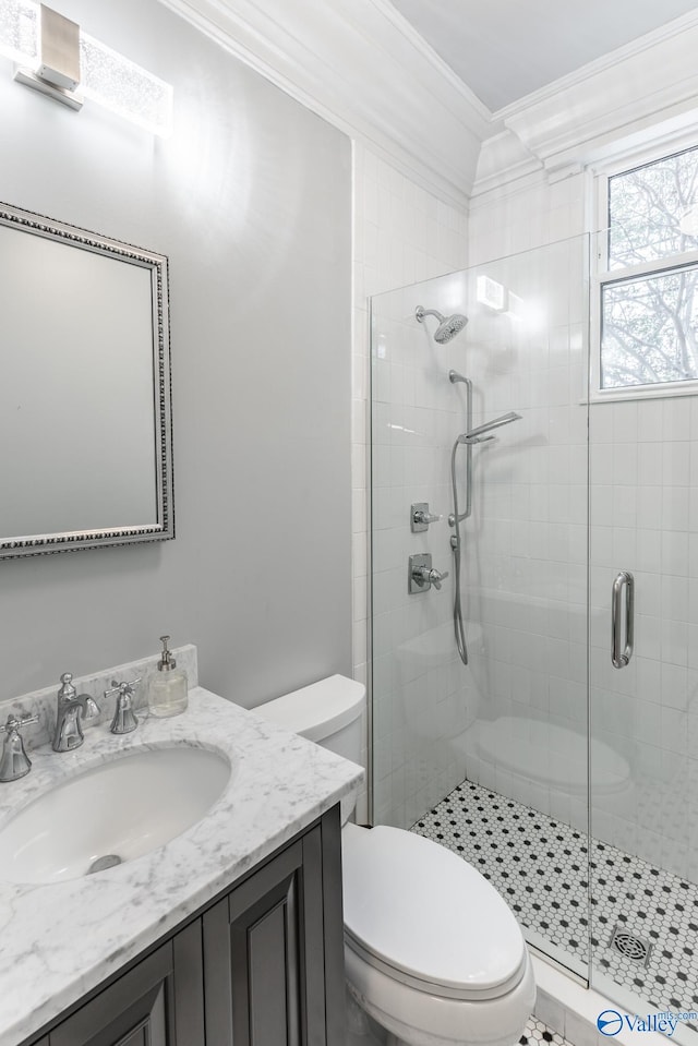 bathroom featuring vanity, toilet, crown molding, and a shower with shower door