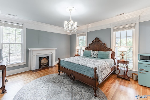 bedroom featuring an inviting chandelier, multiple windows, ornamental molding, and hardwood / wood-style flooring