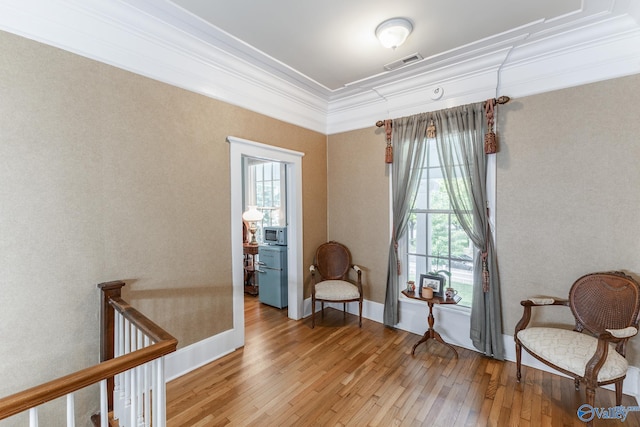 living area with a wealth of natural light, ornamental molding, and wood-type flooring