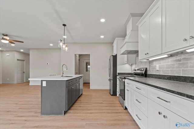 kitchen with sink, white cabinetry, appliances with stainless steel finishes, pendant lighting, and a kitchen island with sink