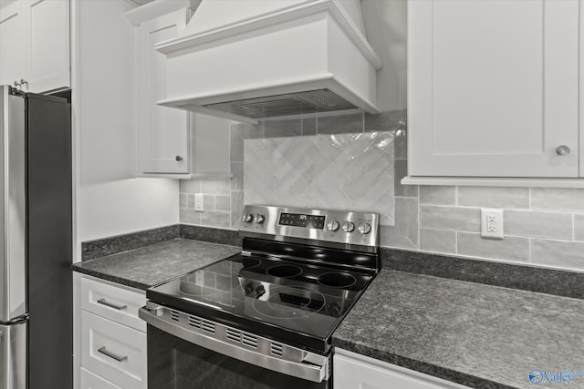 kitchen featuring tasteful backsplash, premium range hood, white cabinets, and appliances with stainless steel finishes