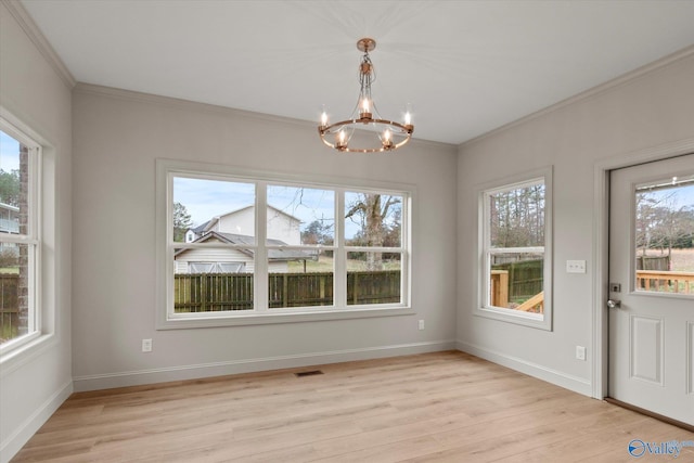 unfurnished dining area with crown molding, a wealth of natural light, an inviting chandelier, and light hardwood / wood-style flooring