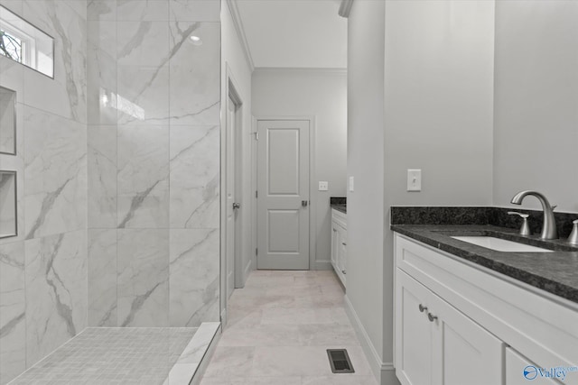 bathroom featuring crown molding, vanity, and a tile shower