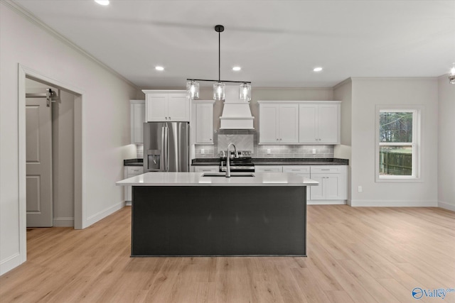 kitchen with white cabinets, sink, pendant lighting, and stainless steel fridge