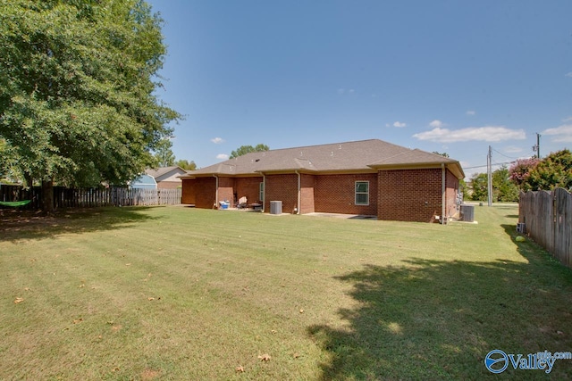 rear view of house featuring central AC unit and a yard