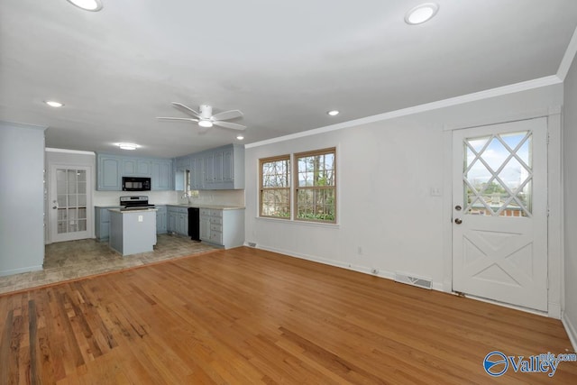 unfurnished living room featuring crown molding, sink, and light hardwood / wood-style floors