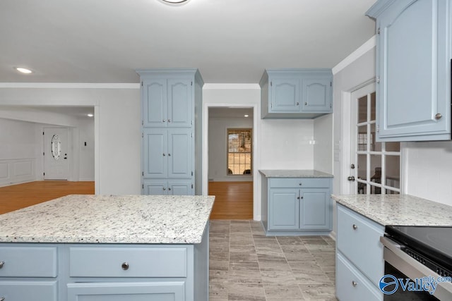 kitchen with crown molding, blue cabinetry, light stone counters, a kitchen island, and decorative backsplash