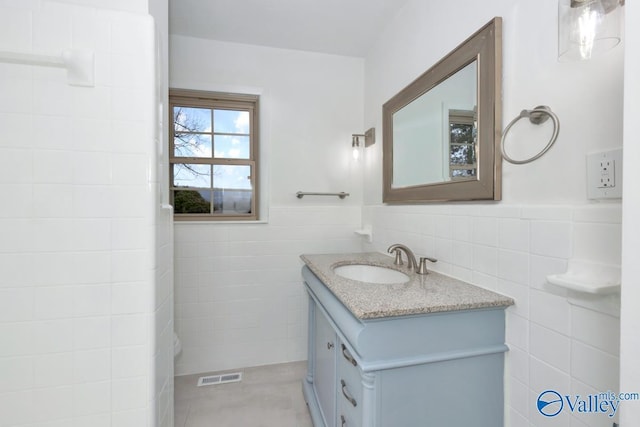 bathroom with vanity and tile walls