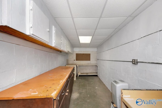 interior space with a drop ceiling and white cabinets