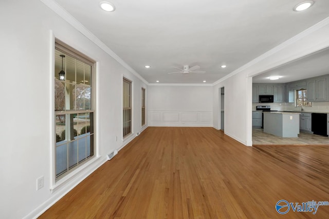 unfurnished living room featuring sink, light hardwood / wood-style flooring, and ornamental molding