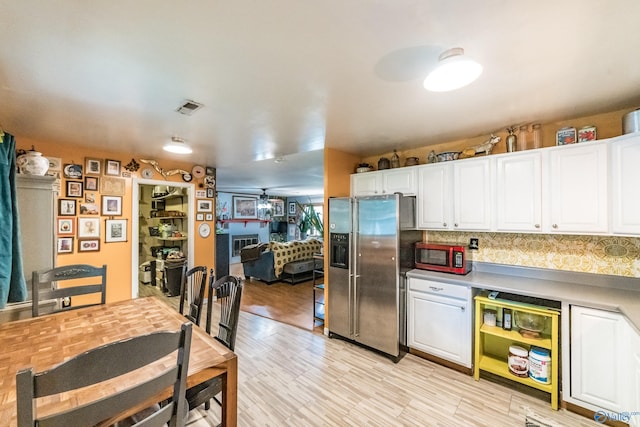 2122 Fernbrook Dr NE, Huntsville, AL 35811 - kitchen with stainless steel fridge, white cabinetry, tasteful backsplash, light countertops, and light wood finished floors