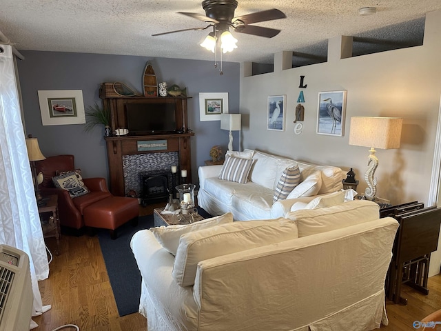 living room featuring heating unit, a textured ceiling, a ceiling fan, and wood finished floors