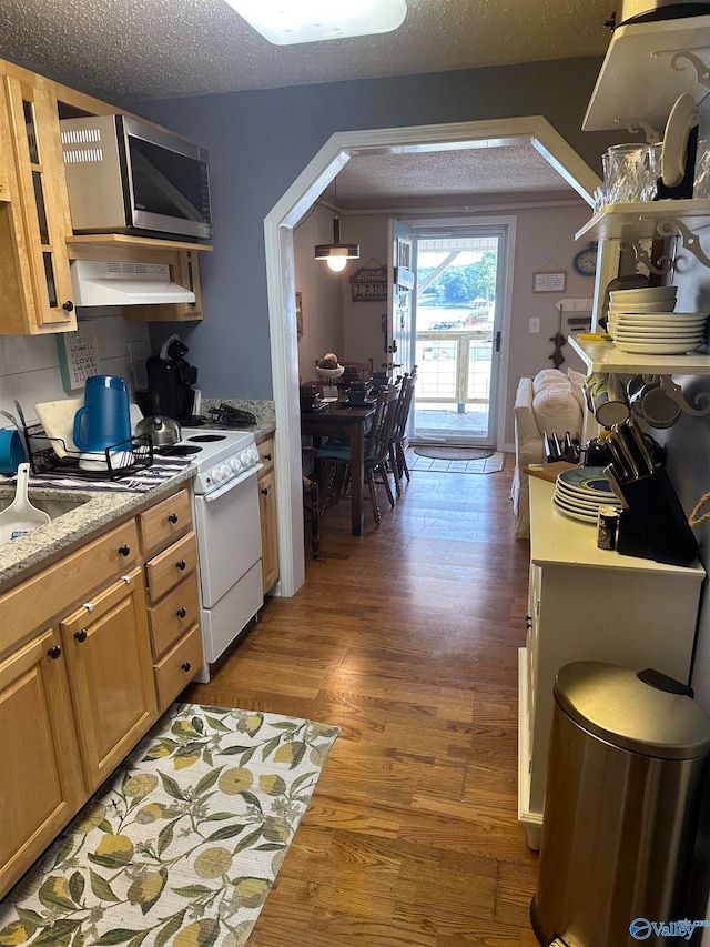 kitchen with decorative light fixtures, white stove, a textured ceiling, wall chimney range hood, and wood-type flooring