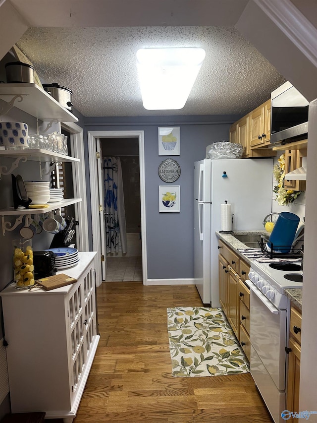 kitchen with a textured ceiling, under cabinet range hood, light wood finished floors, stainless steel microwave, and pendant lighting