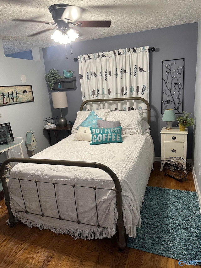 bedroom with a textured ceiling, ceiling fan, and dark hardwood / wood-style flooring