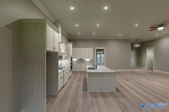 kitchen with light wood-type flooring, a kitchen island with sink, a sink, and recessed lighting