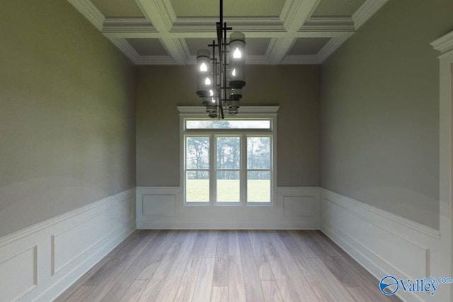 unfurnished dining area with wainscoting, coffered ceiling, a notable chandelier, and wood finished floors