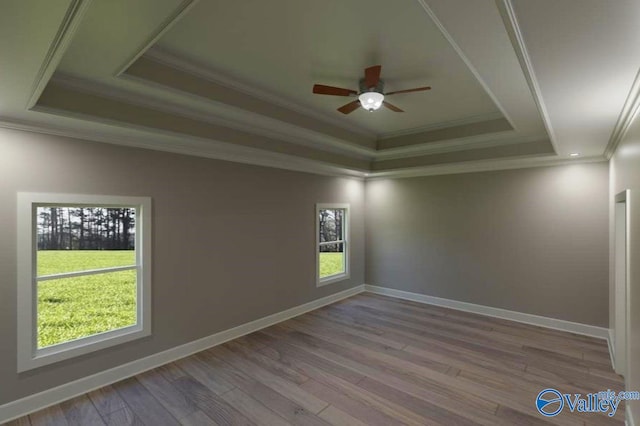 unfurnished room featuring baseboards, a tray ceiling, wood finished floors, and ornamental molding