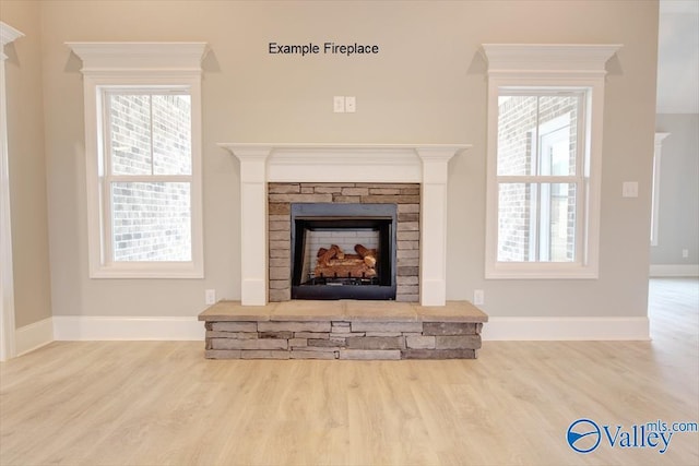 details featuring a stone fireplace, baseboards, and wood finished floors