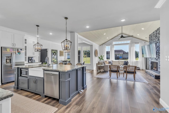 kitchen featuring an island with sink, lofted ceiling, gray cabinetry, white cabinetry, and stainless steel appliances