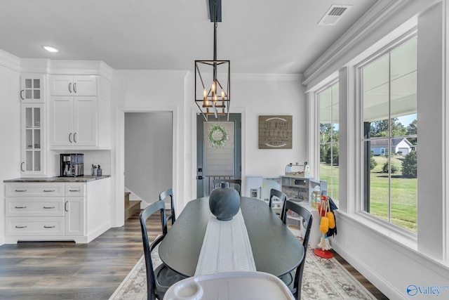 dining room with ornamental molding, a healthy amount of sunlight, an inviting chandelier, and dark hardwood / wood-style flooring