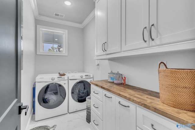 clothes washing area featuring cabinets, crown molding, and washer and dryer