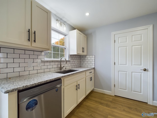 kitchen with dark hardwood / wood-style flooring, light stone counters, sink, tasteful backsplash, and stainless steel dishwasher