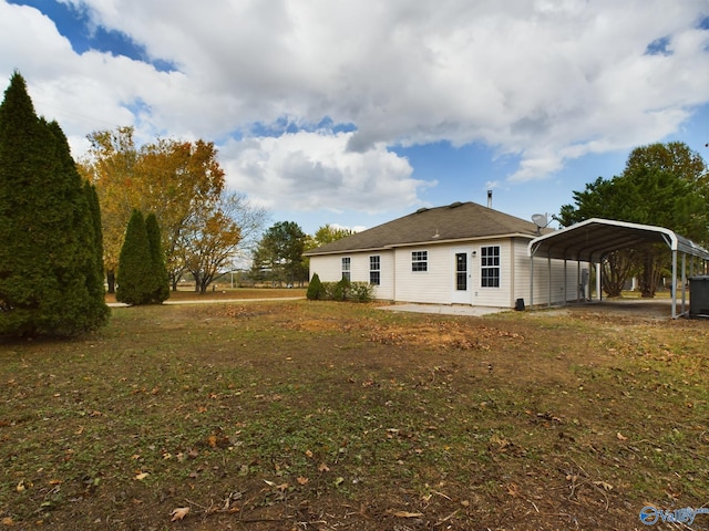 rear view of property featuring a carport and a yard