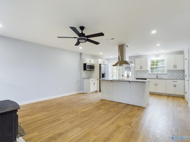 kitchen featuring island range hood, a kitchen island, white cabinetry, appliances with stainless steel finishes, and light wood-type flooring