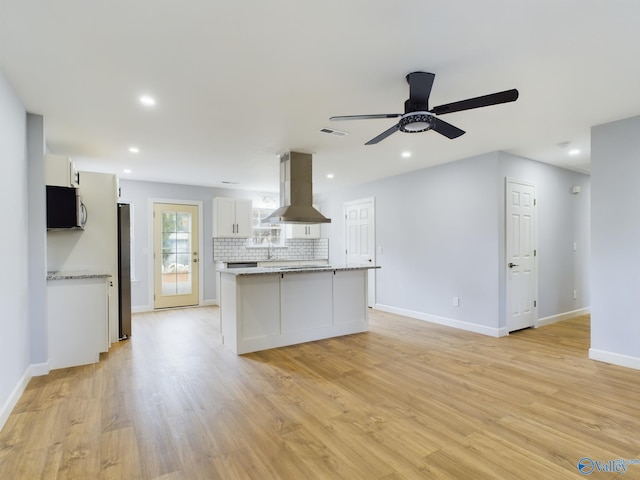 kitchen with white cabinets, island range hood, light wood-type flooring, and stainless steel appliances