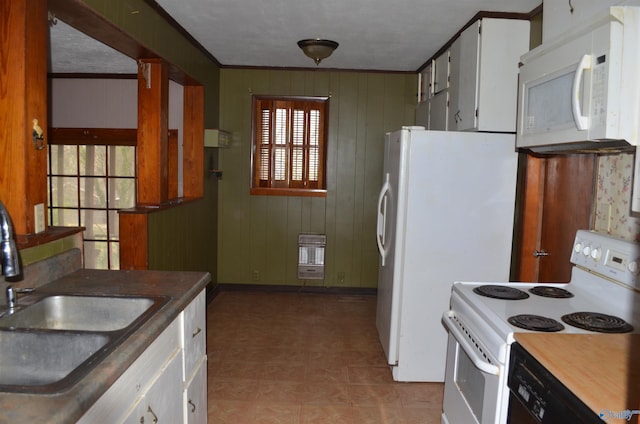 kitchen with heating unit, a sink, wood walls, white appliances, and white cabinets