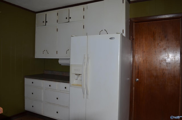 kitchen featuring white cabinets, dark countertops, and white fridge with ice dispenser