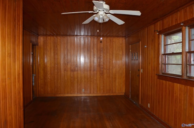 unfurnished room featuring wooden walls, ceiling fan, and wood finished floors