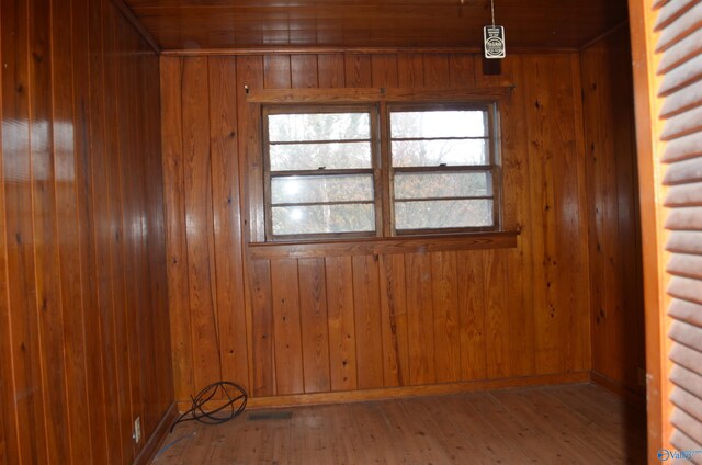 empty room featuring baseboards, wood walls, and wood-type flooring