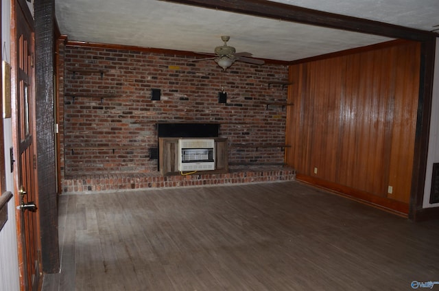 unfurnished living room featuring heating unit, wood finished floors, ceiling fan, and wood walls