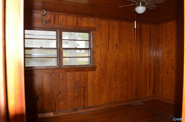spare room with a ceiling fan and wood walls