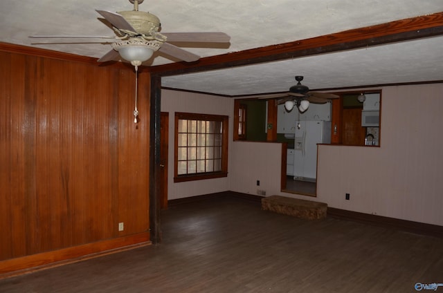 spare room featuring wood walls, crown molding, baseboards, a ceiling fan, and wood finished floors