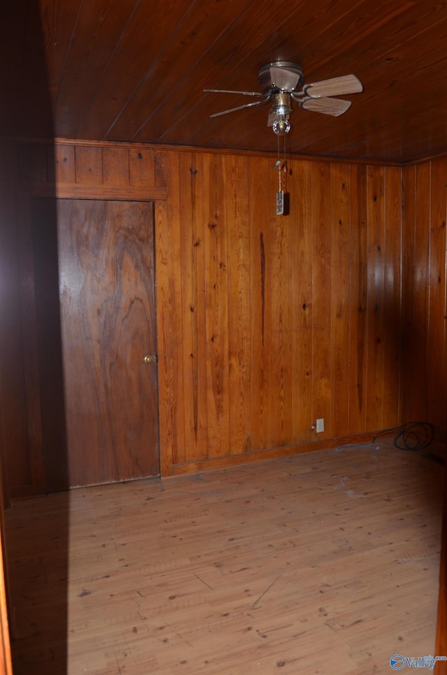 spare room featuring wood ceiling, wooden walls, a ceiling fan, and hardwood / wood-style floors