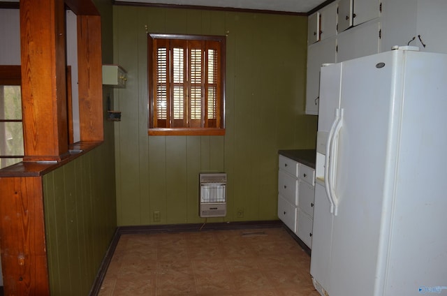 kitchen featuring heating unit, white refrigerator with ice dispenser, dark countertops, and white cabinets