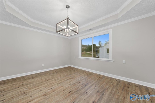 unfurnished room featuring an inviting chandelier, hardwood / wood-style flooring, a raised ceiling, a textured ceiling, and crown molding