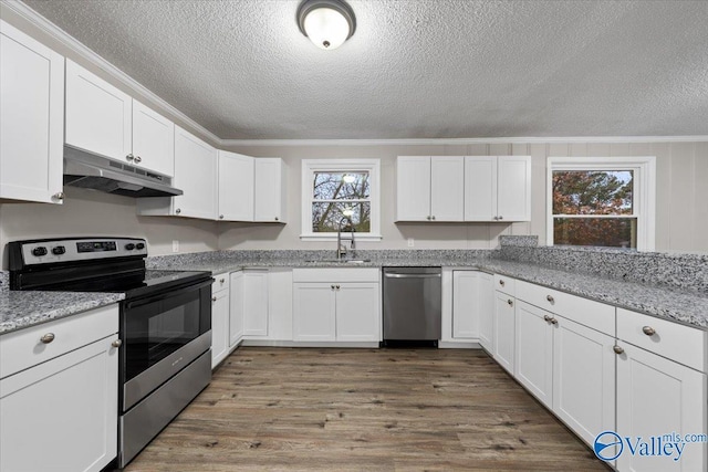 kitchen with light stone countertops, white cabinets, stainless steel appliances, sink, and crown molding