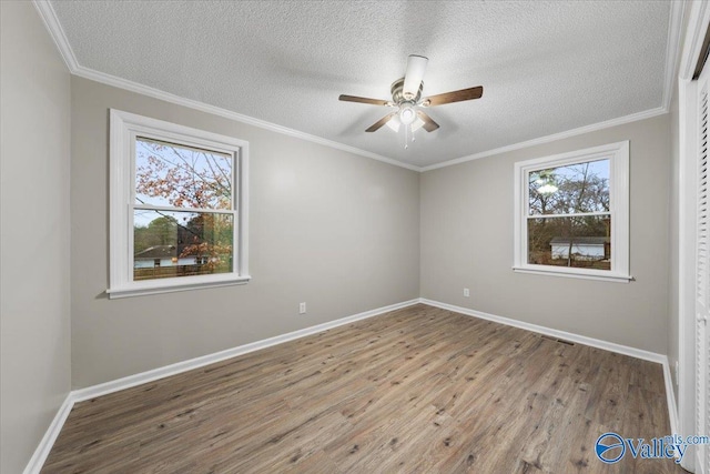 empty room with ceiling fan, plenty of natural light, a textured ceiling, and light wood-type flooring