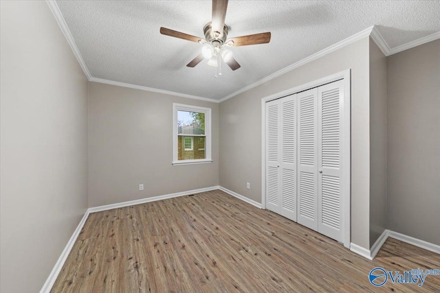 unfurnished bedroom with ceiling fan, light wood-type flooring, a textured ceiling, ornamental molding, and a closet