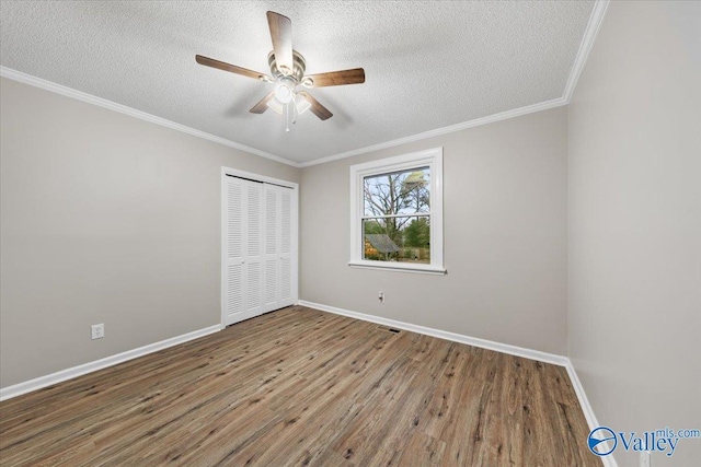 unfurnished bedroom with a textured ceiling, hardwood / wood-style flooring, a closet, ornamental molding, and ceiling fan