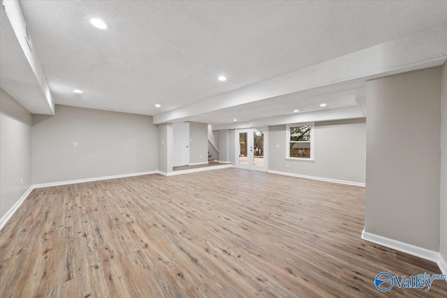 basement featuring a textured ceiling and light hardwood / wood-style flooring