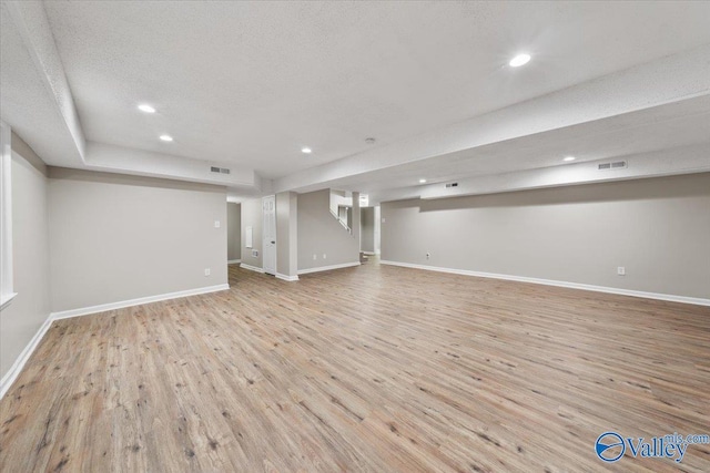 basement featuring light hardwood / wood-style floors and a textured ceiling